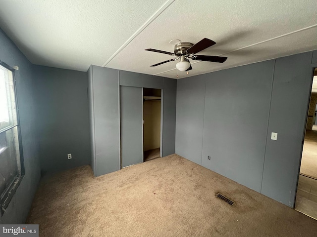 unfurnished bedroom with carpet floors, a textured ceiling, and ceiling fan