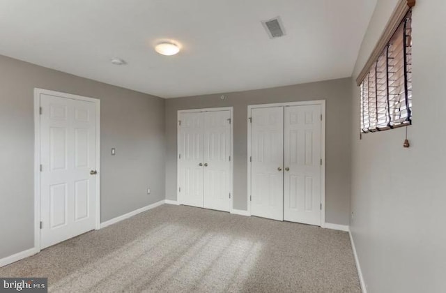 unfurnished bedroom featuring two closets and carpet floors