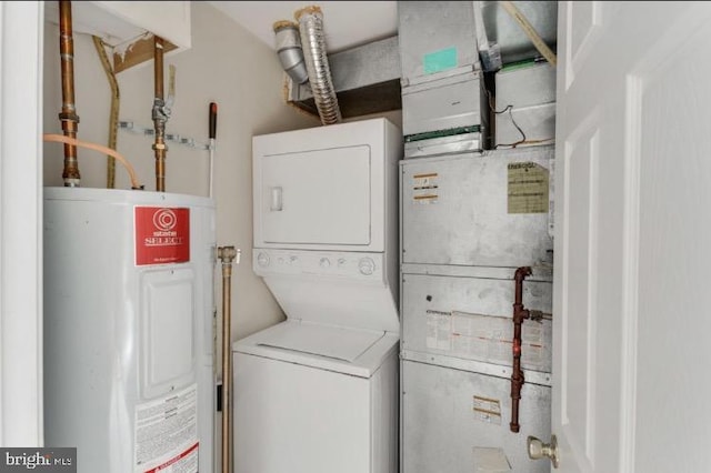 clothes washing area featuring stacked washer and clothes dryer and electric water heater