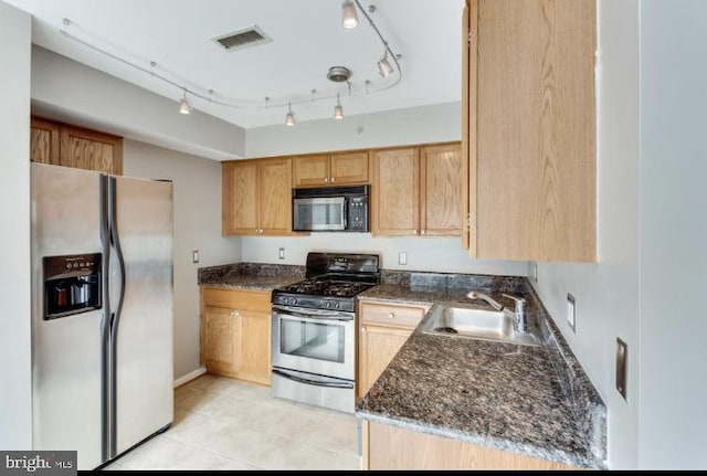 kitchen featuring light tile patterned floors, sink, appliances with stainless steel finishes, and dark stone countertops