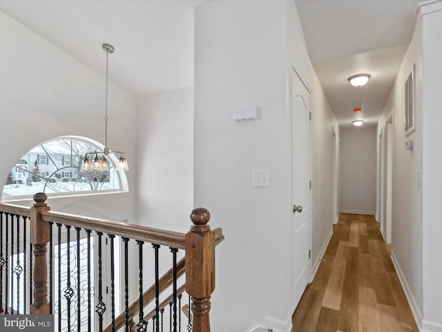 corridor with hardwood / wood-style flooring and a notable chandelier