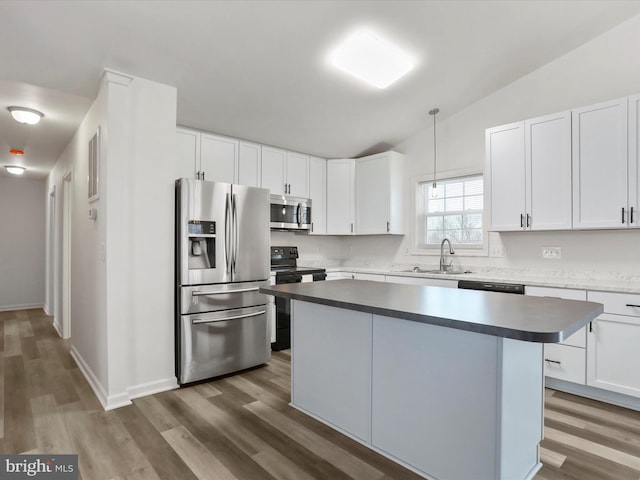 kitchen with sink, appliances with stainless steel finishes, hanging light fixtures, white cabinets, and a kitchen island