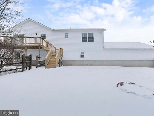 snow covered rear of property with a deck