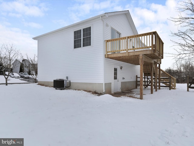 view of snowy exterior with central air condition unit and a deck