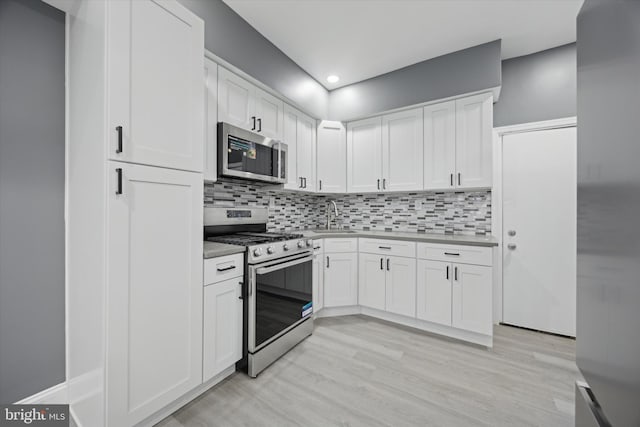 kitchen featuring light wood-type flooring, appliances with stainless steel finishes, sink, and white cabinets