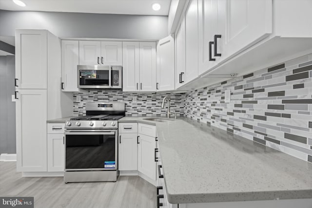 kitchen with stainless steel appliances, white cabinets, and light stone counters