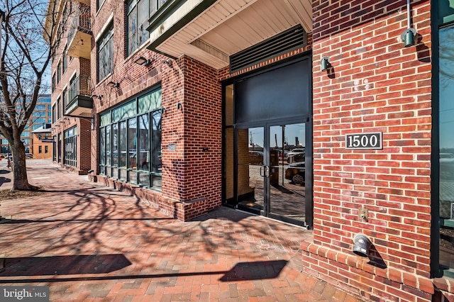 view of exterior entry featuring french doors and brick siding