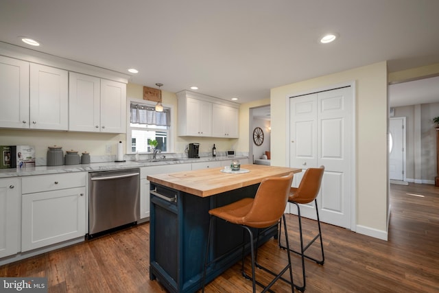 kitchen with white cabinets, a center island, stainless steel dishwasher, and butcher block countertops