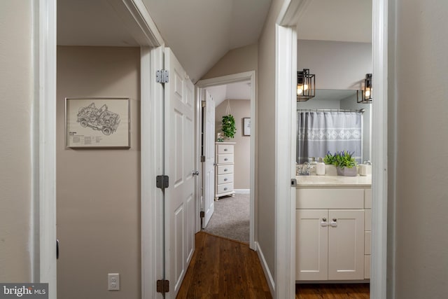 corridor with sink, dark hardwood / wood-style flooring, and lofted ceiling