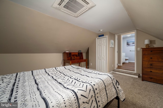 bedroom featuring a closet, vaulted ceiling, ensuite bathroom, and carpet floors