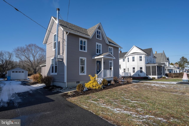 view of front of home featuring a garage, a sunroom, a front yard, and an outdoor structure