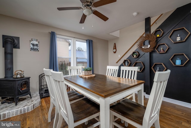 dining area featuring a wood stove, ceiling fan, and hardwood / wood-style flooring