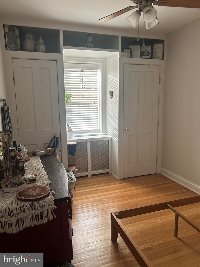 bedroom with ceiling fan, radiator heating unit, and wood-type flooring