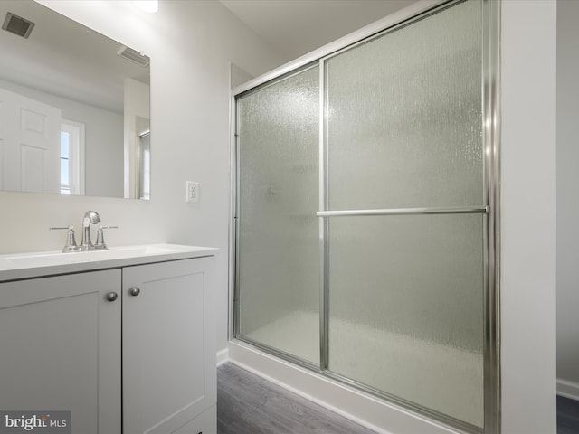 bathroom featuring hardwood / wood-style flooring, vanity, and a shower with door