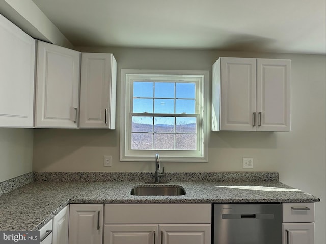 kitchen with sink, stainless steel dishwasher, white cabinets, and light stone countertops