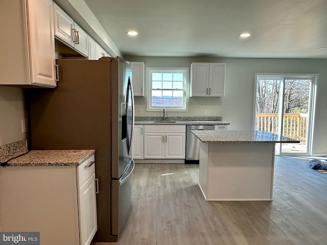 kitchen featuring light hardwood / wood-style flooring, sink, appliances with stainless steel finishes, white cabinetry, and light stone countertops