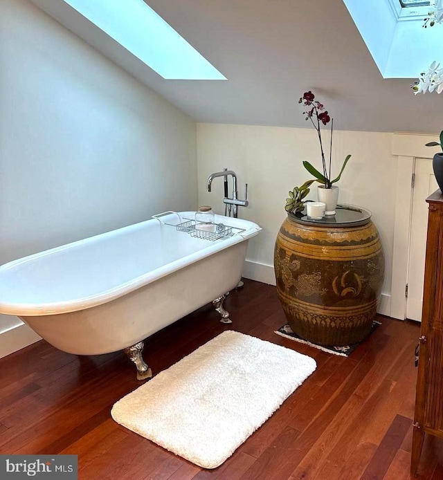 bathroom featuring a bathing tub, hardwood / wood-style floors, and vaulted ceiling with skylight