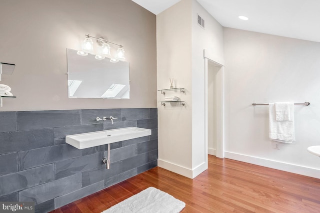 bathroom featuring wood-type flooring, vaulted ceiling, and sink