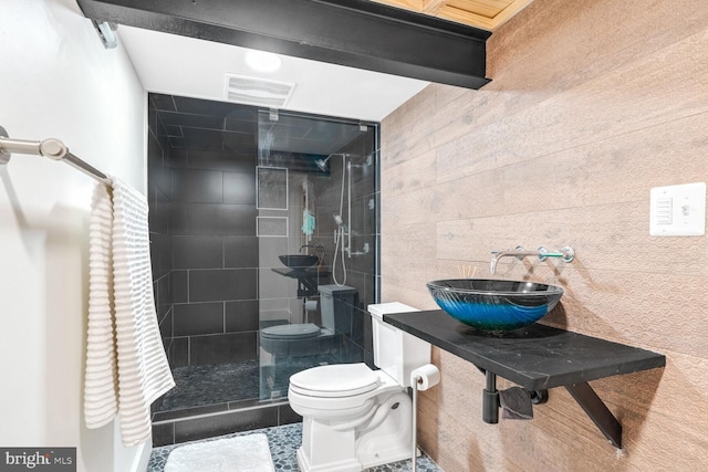 bathroom featuring a shower with door, sink, and toilet