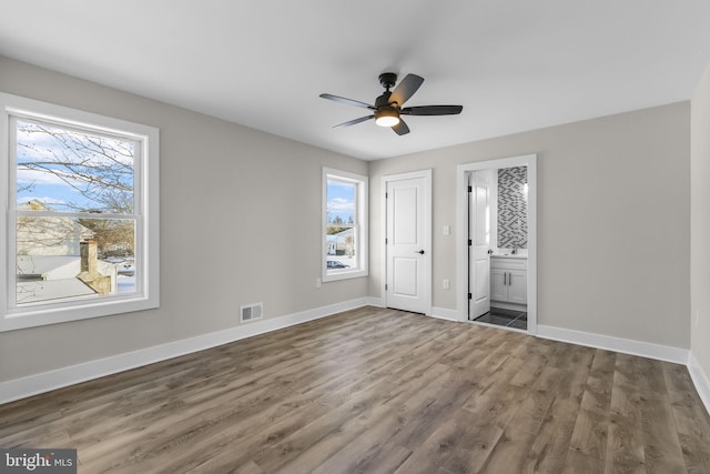 unfurnished bedroom featuring ceiling fan, connected bathroom, and dark hardwood / wood-style flooring