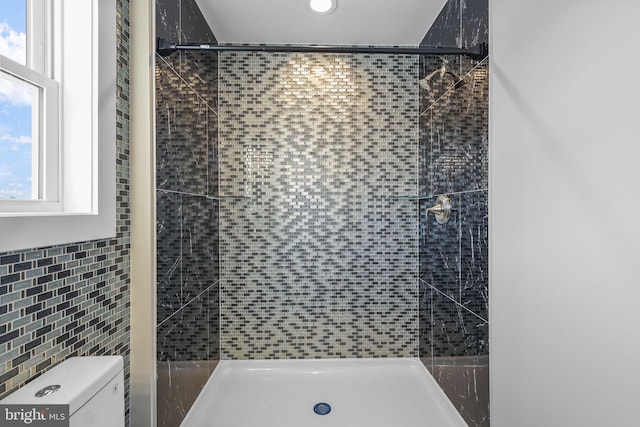 bathroom with toilet, tile walls, and tiled shower