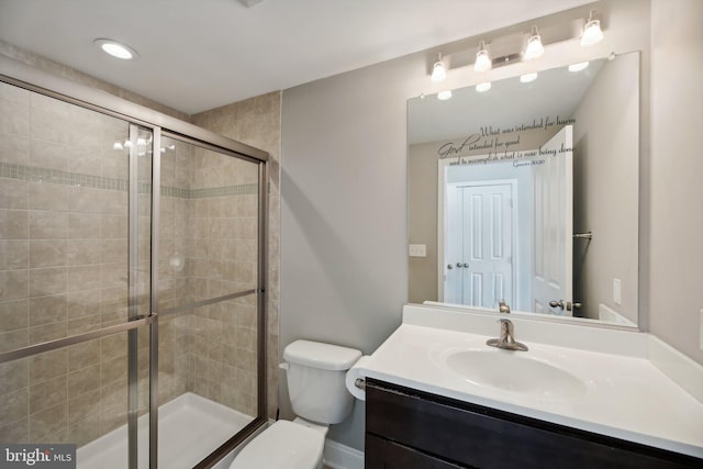 bathroom with vanity, toilet, and a shower with door