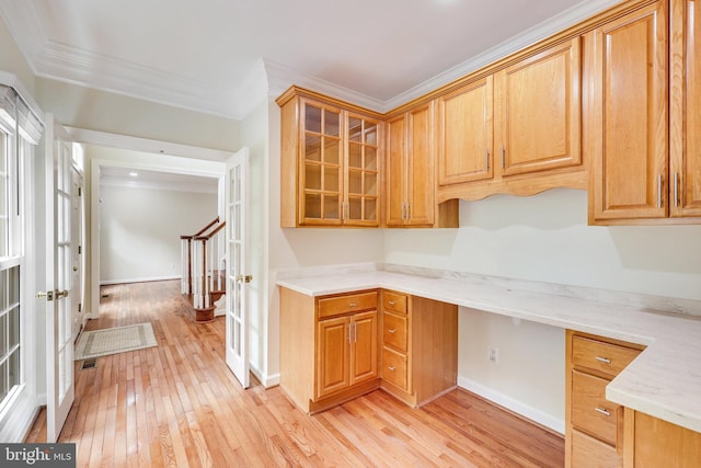 kitchen with light stone countertops, light hardwood / wood-style flooring, ornamental molding, and built in desk