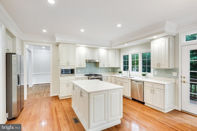 kitchen with sink, a kitchen island, stainless steel appliances, and white cabinetry