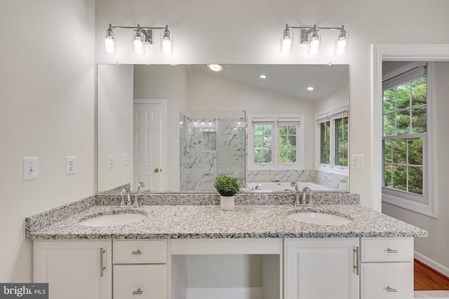 bathroom featuring wood-type flooring, walk in shower, vanity, and vaulted ceiling