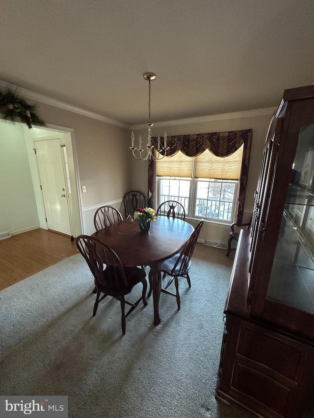 dining area featuring crown molding, carpet flooring, and a chandelier