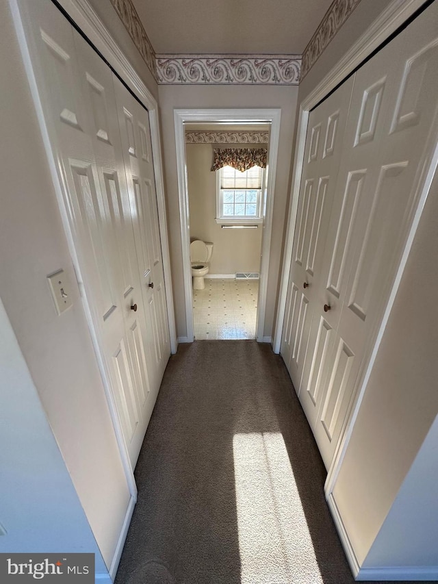 hallway with dark colored carpet