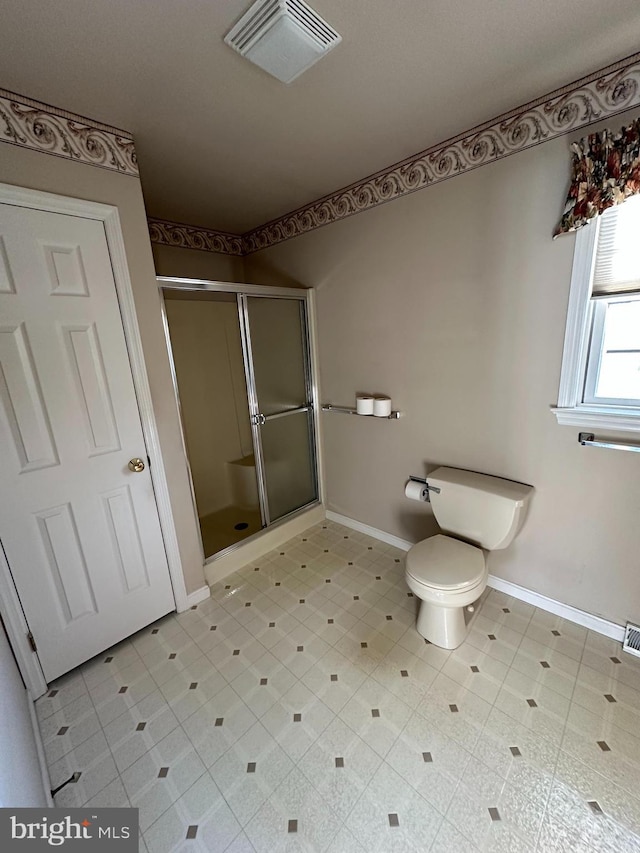 bathroom with a shower with door and toilet