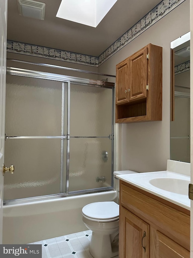 full bathroom with vanity, a skylight, shower / bath combination with glass door, and toilet