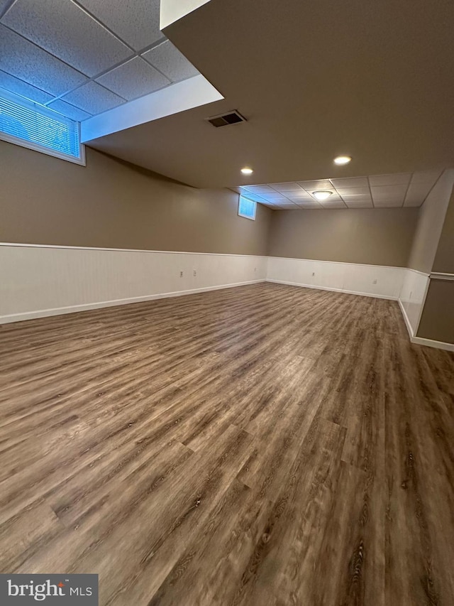 basement featuring a drop ceiling and wood-type flooring