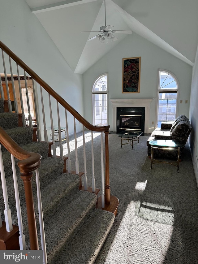 stairs with ceiling fan, a fireplace, vaulted ceiling, and carpet flooring