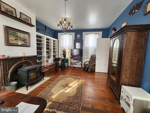 living room featuring a wood stove, a chandelier, built in shelves, and dark hardwood / wood-style floors