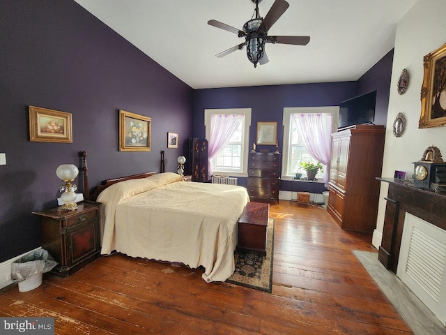 bedroom with ceiling fan, radiator heating unit, and dark hardwood / wood-style flooring