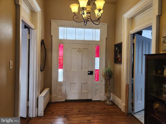 foyer with wood-type flooring, radiator heating unit, and a notable chandelier