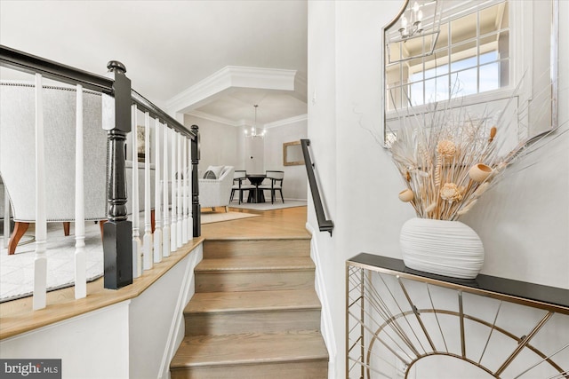 stairway with a notable chandelier and crown molding