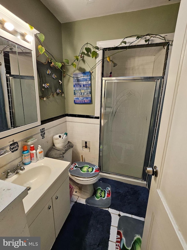 bathroom with vanity, toilet, an enclosed shower, and tile walls