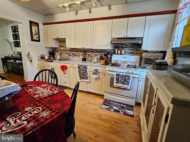 kitchen with white cabinetry, decorative backsplash, gas range gas stove, and light hardwood / wood-style flooring