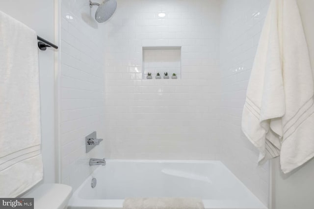 bathroom with toilet and tiled shower / bath