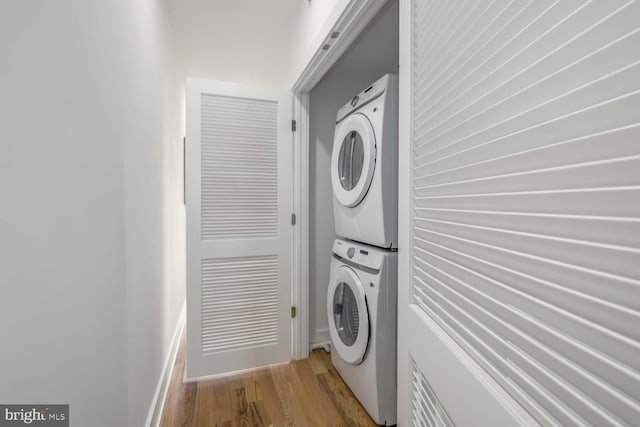 clothes washing area with light hardwood / wood-style floors and stacked washer / dryer