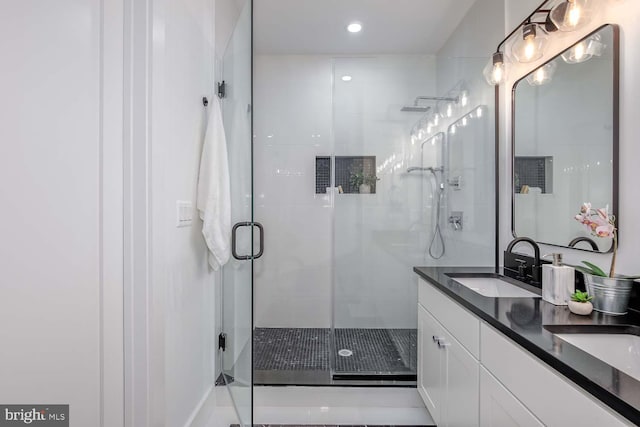 bathroom featuring a shower with shower door and vanity