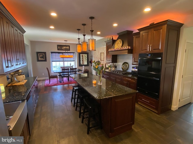 kitchen featuring pendant lighting, custom range hood, dark stone counters, and a kitchen island