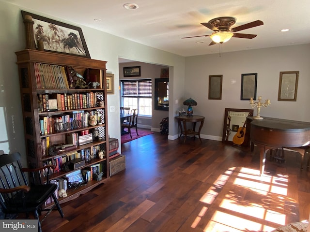 sitting room with dark wood-type flooring and ceiling fan