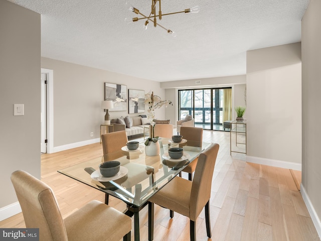 dining area with a textured ceiling, a chandelier, and light hardwood / wood-style floors