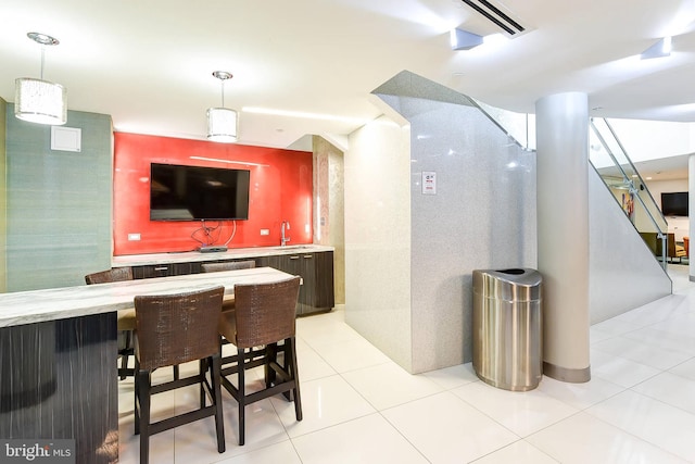 bar with pendant lighting, sink, and light tile patterned floors