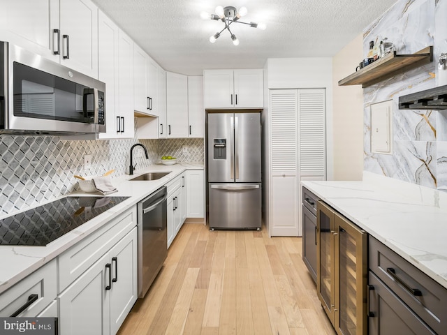 kitchen with wine cooler, sink, light wood-type flooring, stainless steel appliances, and white cabinets