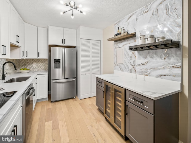 kitchen with sink, white cabinets, beverage cooler, stainless steel appliances, and a textured ceiling